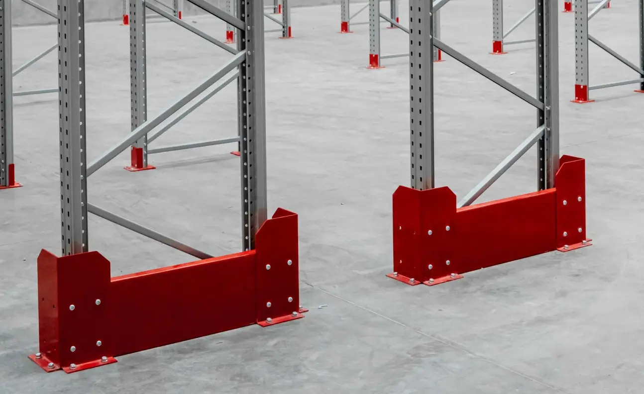 Red pallet racking upright protectors installed at base of warehouse storage frames for impact protection